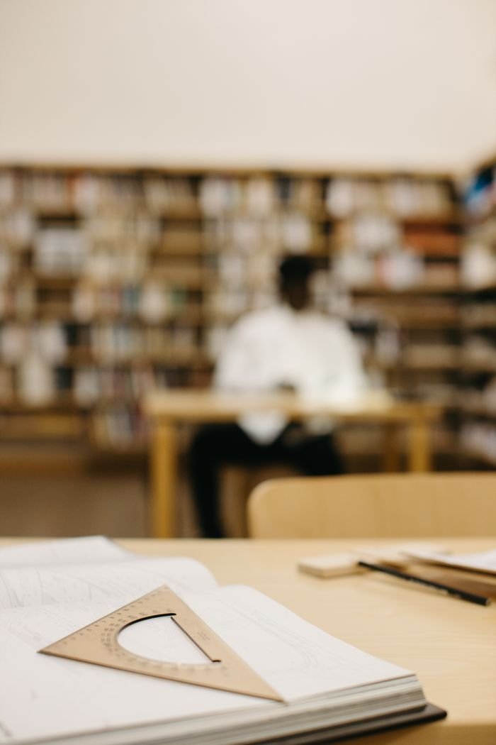 digital Focused image depicting a drafting triangle on a study desk in a library setting.